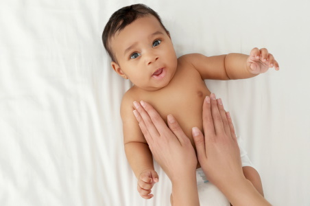 A baby gets their tummy massaged for constipation