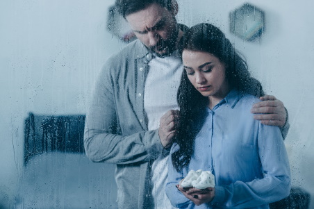 Bereaved parents look sadly at some baby shoes